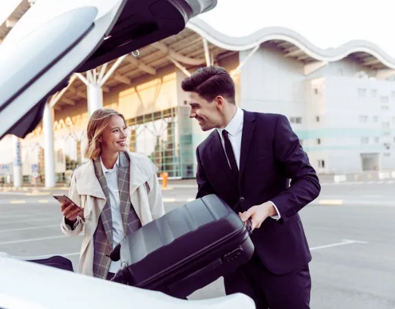 A professional chauffeur assists a client with their luggage at the airport.