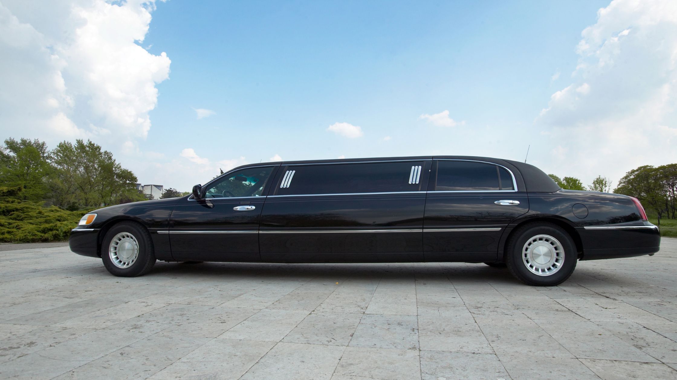Black stretch limousine parked outdoors under blue sky Black stretch limousine parked outdoors under blue sky