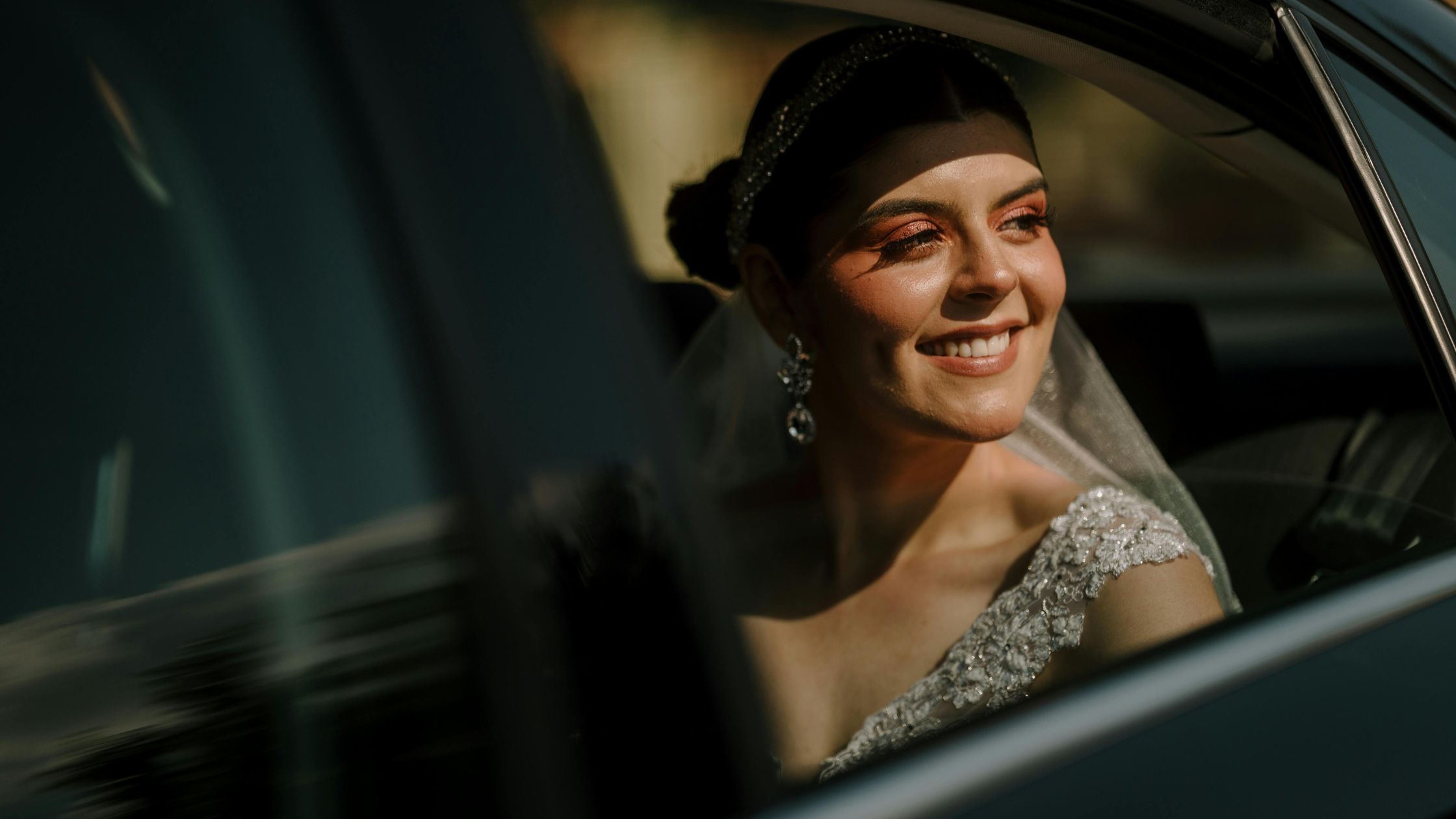 Smiling bride in wedding dress looking out car window Smiling bride in wedding dress looking out car window