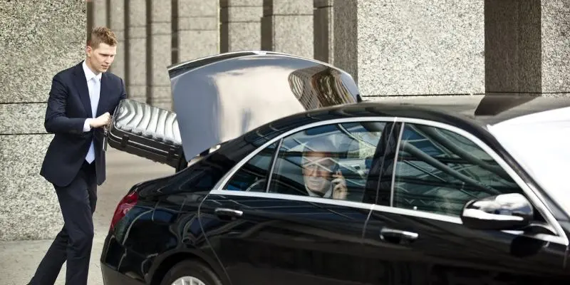 Professional chauffeur loading luggage into a luxury car for a business client in Bellevue