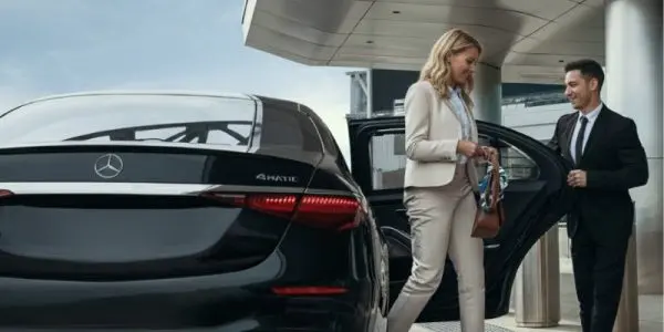 Professional chauffeur opening a Mercedes sedan door for a business traveler in Bellevue