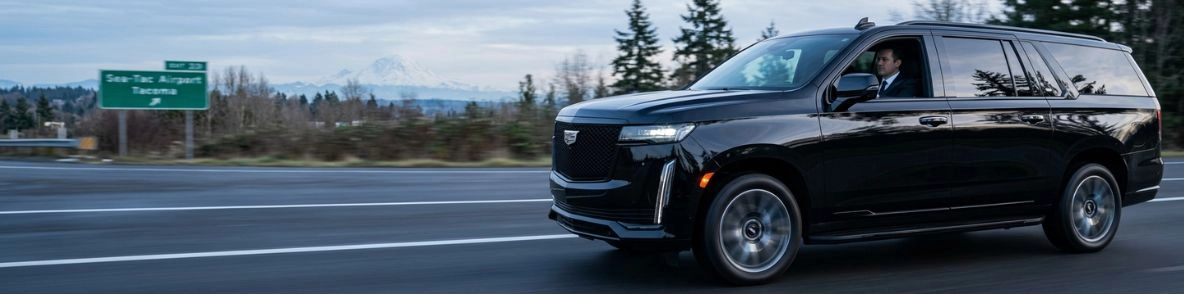 black cadillac escalade driving on highway near airport