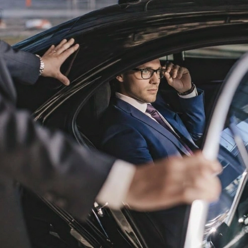 businessman getting into black car with driver assistance businessman getting into black car with driver assistance