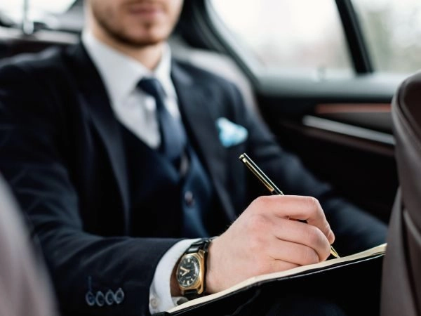 businessman writing notes in back seat during black car service seattle ride businessman writing notes in back seat during black car service seattle ride